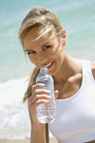 Woman+drinking+water+on+beach.