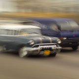 Blurred+view+of+a+car+and+a+van+on+a+road%2C+Havana%2C+Cuba