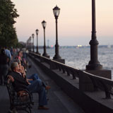 People+sitting+on+benches+along+the+esplanade+at+Battery+Park%2C+New+York+City