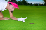 Golf+green+hole+course+woman+humor+flicking+hand+a+ball+inside+in+short+putt
