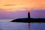 Sunrise+lighthouse+glowing+in+blue+purple+sea+and+orange+sky