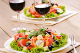 Greek salad and glasses of red wine