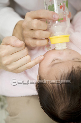 ミルクを飲む赤ちゃんと両親の手