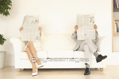 ソファで新聞を読む夫婦