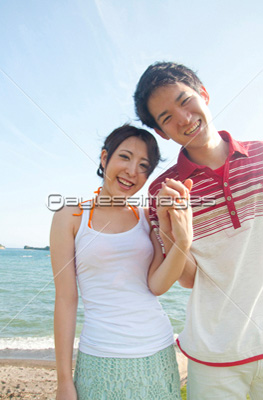 海辺で手を繋ぐカップル