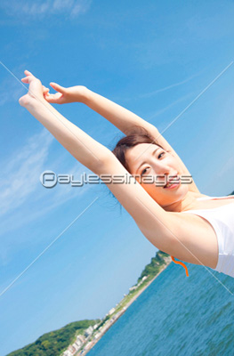 海辺で伸びをする女性