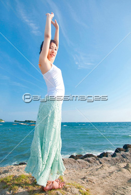 海辺で伸びをする女性