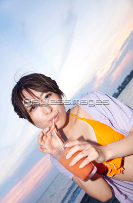 海辺でカクテルを飲む女性