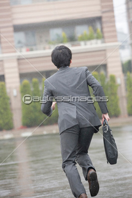 雨の中を走るビジネスマンの後ろ姿 ストックフォトの定額制ペイレス