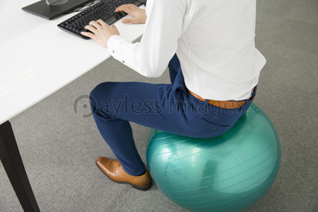 バランスボールに座って仕事をする男性 商用利用可能な写真素材 イラスト素材ならストックフォトの定額制ペイレスイメージズ