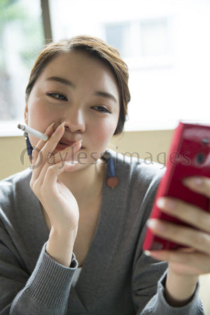 タバコを吸いながら携帯電話を見る女性 商用利用可能な写真素材 イラスト素材ならストックフォトの定額制ペイレスイメージズ