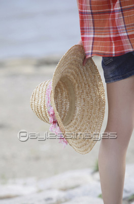 海辺で麦わら帽子を持った女性の手元