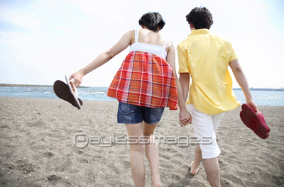 海辺を歩くカップルの後姿