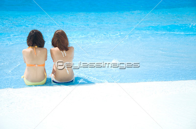 プールサイドに座る水着女性2人の後姿 ストックフォトの定額制ペイレスイメージズ