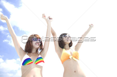 サングラスをかけて手を上げる水着姿の女性2人