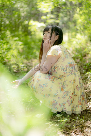 新緑の前でしゃがむ女性 ストックフォトの定額制ペイレスイメージズ