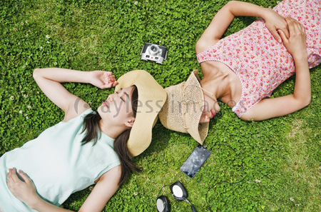芝生に寝転ぶ二人の女性 ストックフォトの定額制ペイレスイメージズ