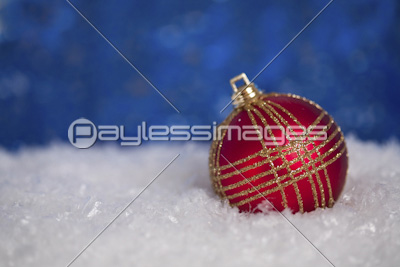 Red,Christmas,tree,decorations,in,snow,on,blue,background,,shallow,depth,of,field