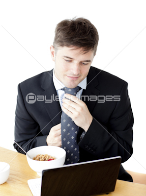 Attractive young businessman making his tie looking at his laptop