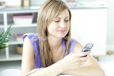 Concentrated blond woman sending a text sititng on a sofa