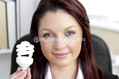 Confident young businesswoman holding a light bulb looking at the camera