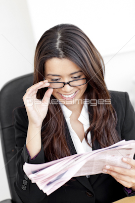 Confident young businesswoman reading newspaper