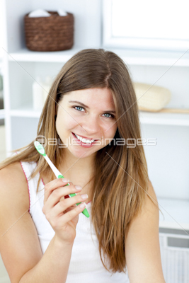 Delighted woman holding a toothbrush smiling at the camera