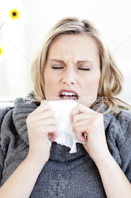 Diseased woman sneezing holding a tissue
