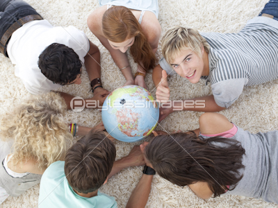 Group of teenagers on the floor examining a terrestrial world and a guy with thumb up