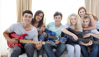 Group of teenagers playing guitar at home
