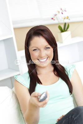 Joyful woman holding a remote smiling at the camera