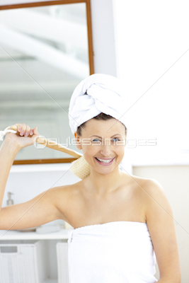 Lively woman washing her back smiling at the camera in the bathroom