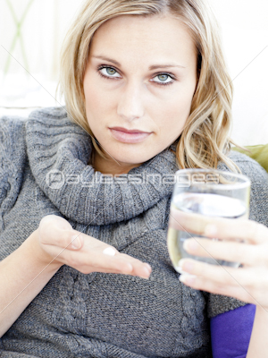 Sick depressed woman holding pills and water looking at the camera