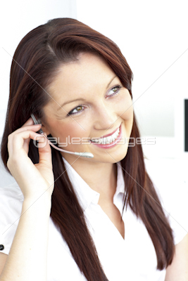 Smiling businesswoman talking on phone using headphones in her office