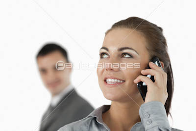 Close up of smiling businesswoman on the phone with colleague behind her