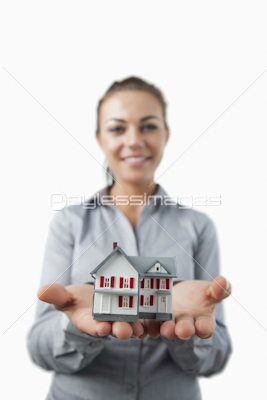 Miniature house being presented by young female estate agent