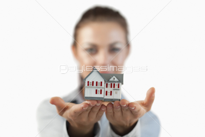 Miniature house being shown by female estate agent