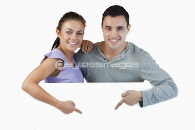 Young couple pointing at advertisement below them