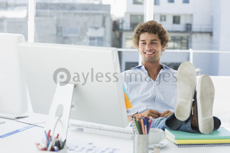 An accidental young man with the leg on the desk of a clever office