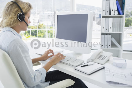 An accidental young woman with the computer which a headset uses