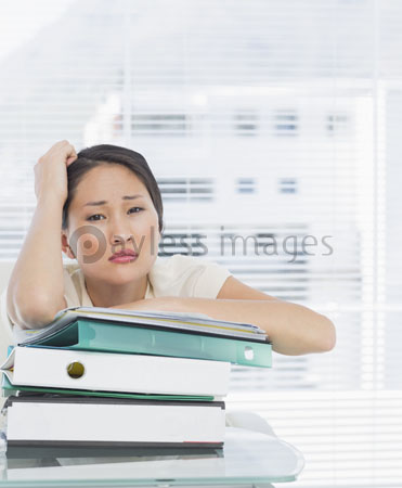 Bored businesswoman with the stack of the folder of a desk