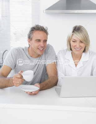 Cheerful couple using laptop in the morning