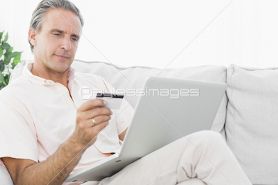 Cheerful man on his couch using tablet pc