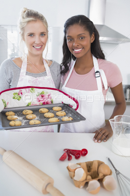 Cheerful woman showing freshly baked cookies to friend