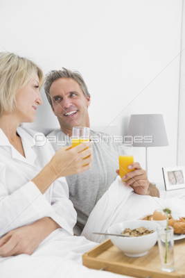 Couple drinking orange juice at breakfast in bed