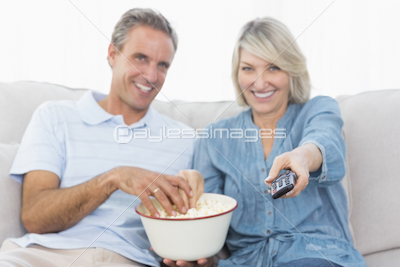 Couple toasting each other with red wine on the sofa