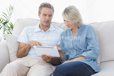 Couple using laptop together on the couch
