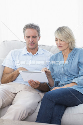 Couple using tablet together on the couch