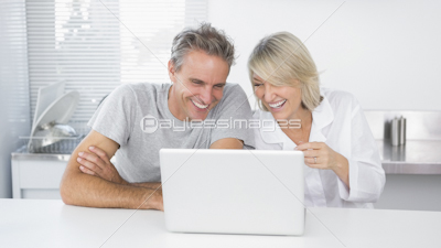 Happy couple using laptop in the morning