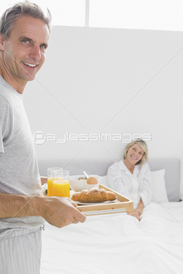 Man bringing breakfast in bed to his partner